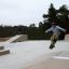 Skateboarder performing a trick on Jump-Ramp at outdoor skatepark.