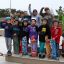 Children with skateboards standing on a Jump-Ramp at a skate park.