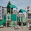 Tower playhouse with a slide on a playground with children playing around
