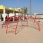 Cross Climber steel structure on a sandy playground.