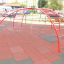 Red Cross Climber steel structure on a playground with safety mats.