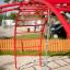 Red Cross Climber steel structure on a playground with sand and a rope hanging.