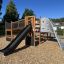 Wooden outdoor playset with a slide and climbing wall, Challenger Aztec in a playground.