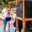 Father helping child climb on Little Jungle Nature play structure.