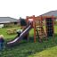 Children playing on Climbing Kiosk Nature playground equipment in a backyard.