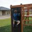 Boy climbing on Climbing Kiosk Nature play structure in suburban park.