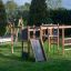 Gorilla Nature wooden playground with slides and climbing structures in a green park.