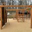 Motor Function Center Nature, wooden playhouse with climbing wall, monkey bars, and slide.