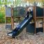 Children playing on Square Play Nature playground slide in an autumn forest.