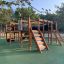 Square Play Nature wooden playground with slides, climbing structures, and tunnels for children.
