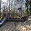 a black playground ship with a slide in the forest