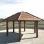 Outdoor wooden gazebo Firehouse with slatted roof structure on a gravel base.