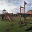 Outdoor playground structure Firehouse with slides, climbing net, and playhouse on a grassy field, s
