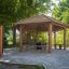Wooden Firehouse gazebo with benches in a green park.
