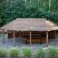 Long Firehouse wooden playground shelter with benches and table in a forest setting