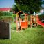 Children's playground with a wooden playhouse, slide, and Hidden corner steel structure.