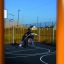 Children playing basketball on Santiago Bernabeu playground with colorful equipment in background.