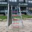Steel play structure with climbing nets installed in a sandy playground.