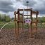 Sherwood wooden playhouse in a park surrounded by trees.