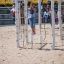 A child playing on a Yellowstone wooden playhouse on a sandy playground.