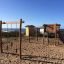Kampinos wooden playhouse with climbing structure and swings by the sea.