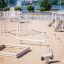 Children's playground equipment Alstad in a sandy outdoor area near a lake.