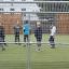 Children playing soccer on the Goal sports field enclosed by metal fencing.