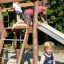 Children playing on a wooden Bergila playground slide.