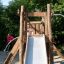 Child playing on Bergila wooden playground slide in a park.