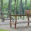 Wooden Dolomiti playground bridge in a lush park.