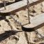 Dolomiti playground swings with wooden seats and metal chains on sand.