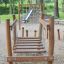 Wooden playground bridge Dolomiti with climbing net in a park setting.