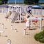 Children playing on Kongo playground structure in a sandy park.