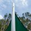 Sun Shade Triangle 3x3x3 Atlantis (Metal) in a forested park setting against a cloudy sky.