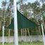 Sun Shade Triangle 3x3x3 Atlantis (Metal) installed in a grassy area with tall trees in the backgrou
