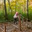 Child playing on Gossamer rope climbing structure in an autumn forest.