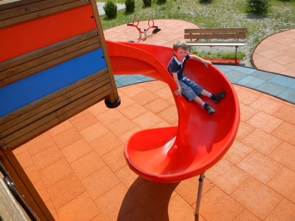 Child playing on a red spiral slide on Rubber Tiles 90
