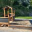 a wooden playhouse with a sandpit