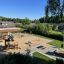 Willa Nature single playhouse in a modern playground setting with surrounding green area.