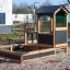 a black wooden playhouse with a sandpit