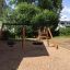 Wooden Playhouse Nature with tire swing and climbing frame in a playground.