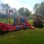 Bus Nature playground equipment on green grass, featuring a red and blue boat structure with slides 