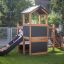 Children playing around the Country House Nature wooden play structure with a slide.