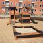 Tower Nature wooden playhouse with slide in a sandy playground area