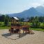Wooden playhouse tower with slide in a scenic outdoor setting.