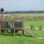 Fortress Nature playhouse with slide on a grassy field with children playing