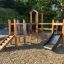Fortress Nature playhouse with slide in a playground setting
