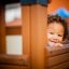 Child playing in Fortress Nature playhouse with slide