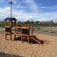 Fortress Nature playhouse with slide in a sandy playground