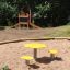 Table and chair set in a playground sandbox with yellow seats.